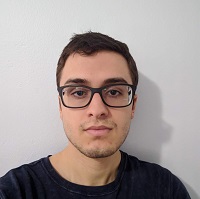 Image of my head and sholders, the background is of a white wall. I am wearing glasses and my tshirt is black.